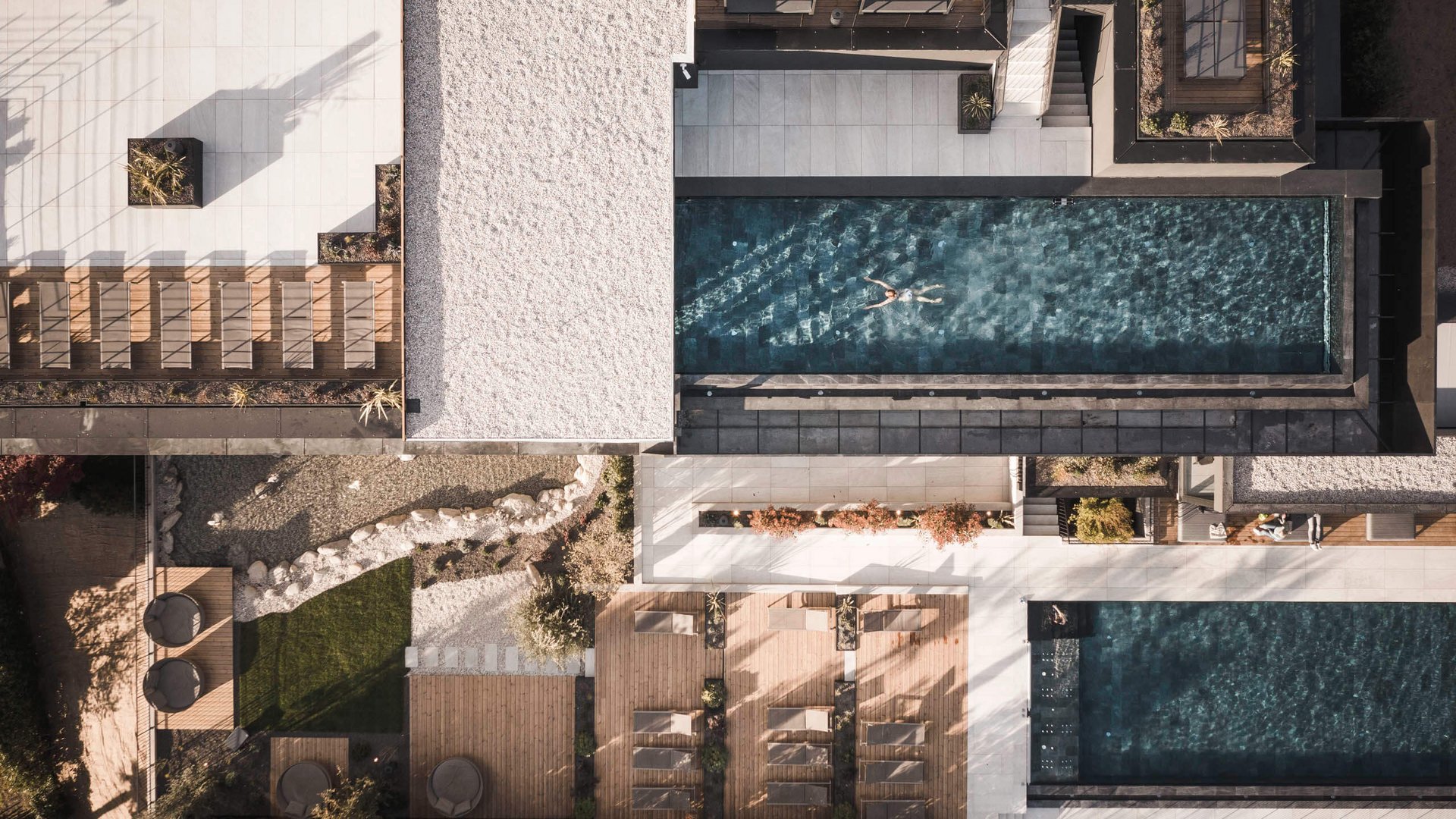 Das wohl schönste Hotel in Dorf Tirol Drohnenansicht eines Pools mit einer Person, umgeben von Liegestühlen und Pflanzen